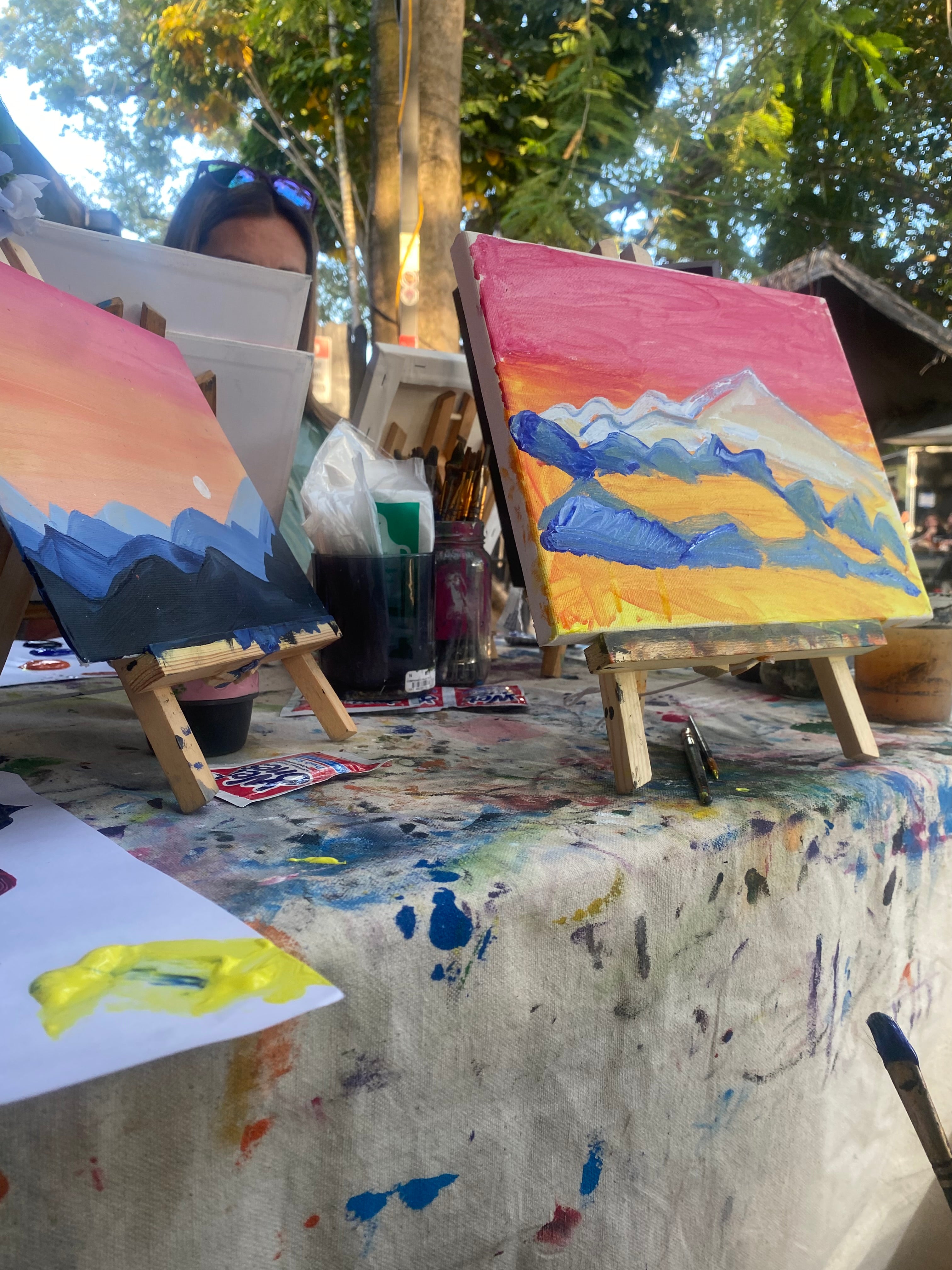 Pink orange yellow blue mountain painting sip and paint art class table set up