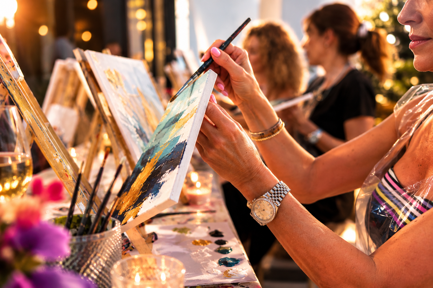 Woman painting at an art event with other participants in the background