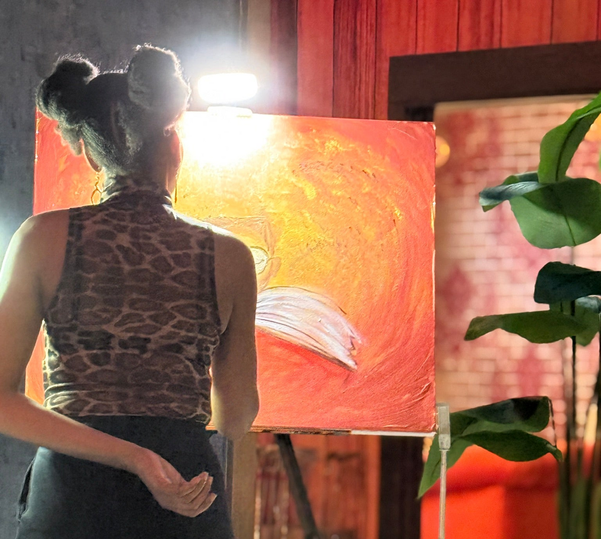 Person painting a large abstract canvas with a bright light source.