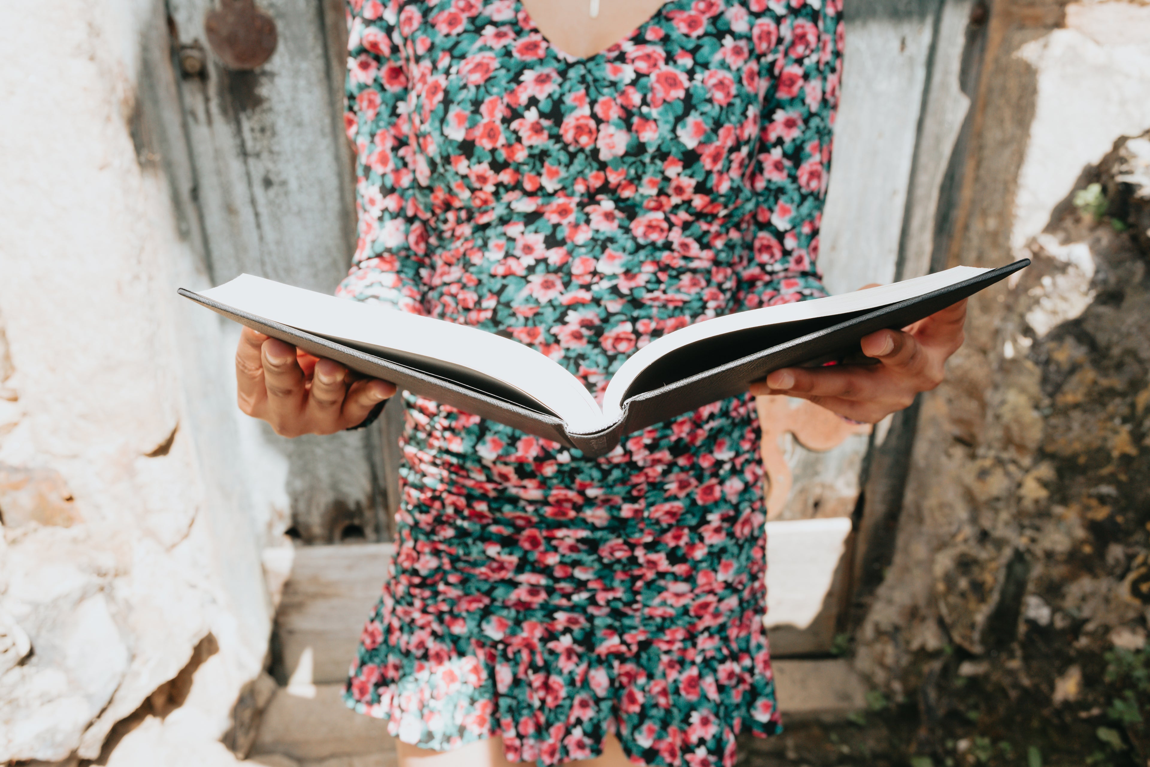 a woman in a floral dress hold a large book open